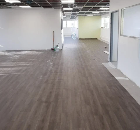 Espace commercial en cours de rénovation avec sol en parquet flottant brun foncé partiellement installé
