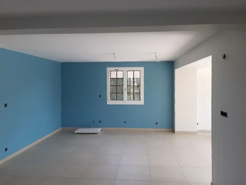 Intérieur d'une maison en cours de rénovation avec mur d'accent bleu turquoise, murs blancs et sol carrelé beige