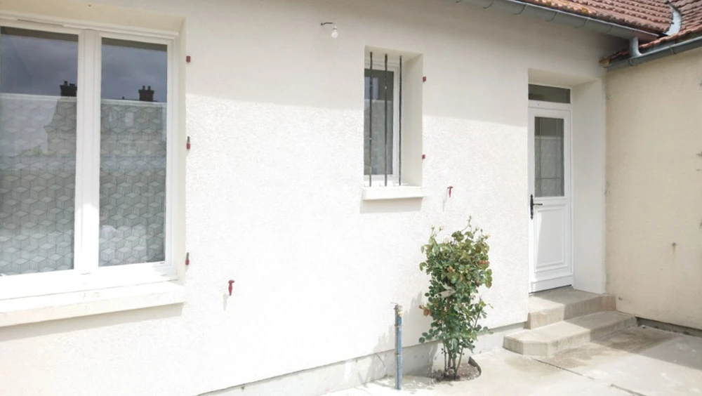 Façade extérieure d'une maison individuelle récemment rénovée avec enduit blanc