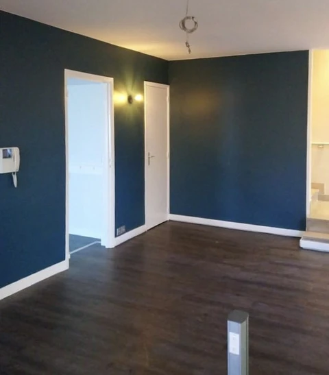 Pièce vide en cours de rénovation avec murs peints en bleu-vert foncé et plafond blanc