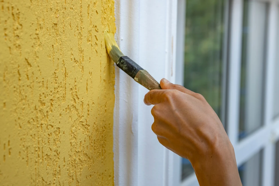 En utilisant le pinceau pour toucher le plafond avec de la peinture blanche, le peintre de maison peint la surface
