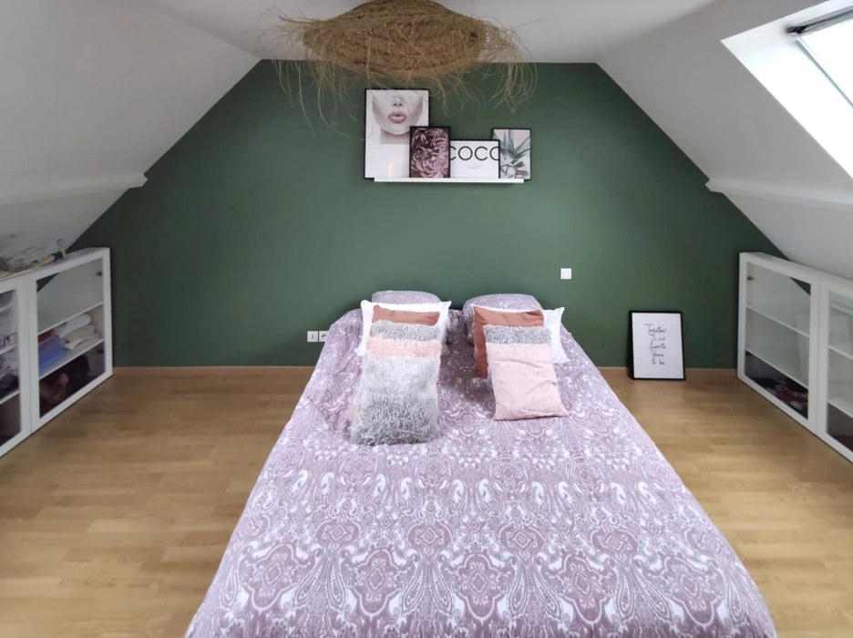 Grande salle vide en cours d'aménagement avec murs bicolores blanc et vert-bleu, plafond suspendu en dalles minérales blanches, sol en béton ciré gris