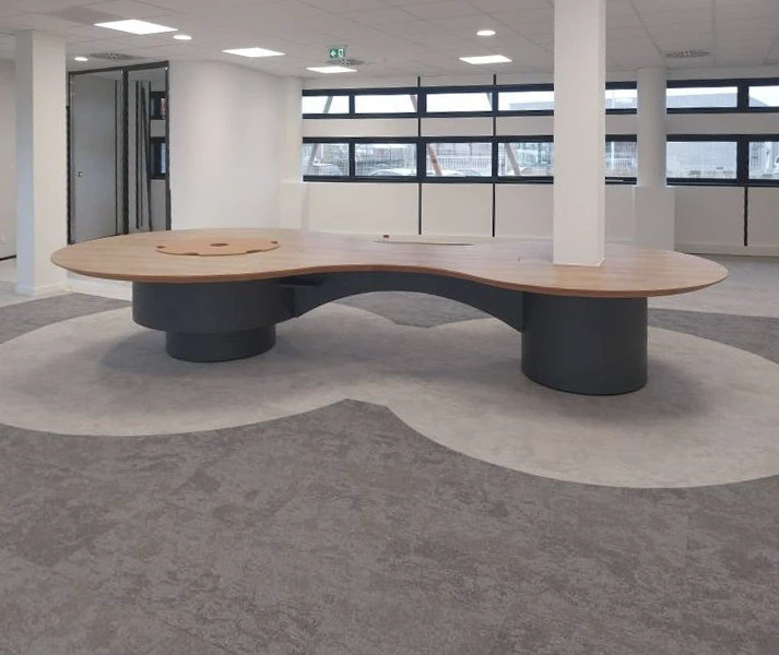 Espace intérieur en cours d'aménagement avec sol en parquet bois naturel, murs en béton brut, bibliothèque murale modulaire en bois clair avec casiers ouverts et fermés